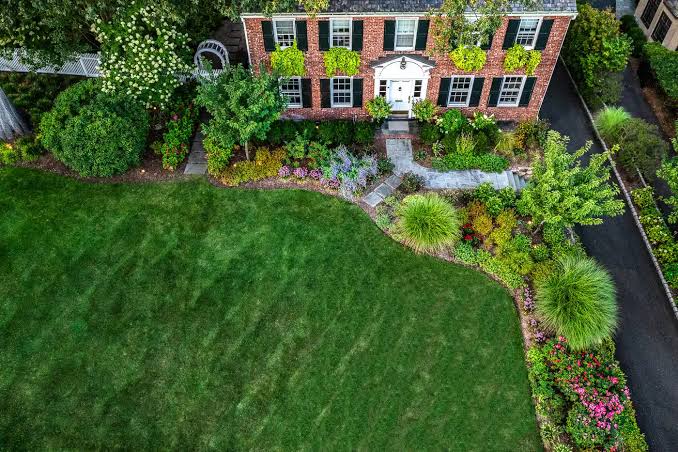 Aerial of a brick colonial with sweeping garden beds