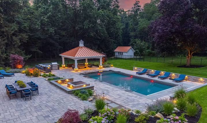 Backyard pool patio at dusk with landscape lighting