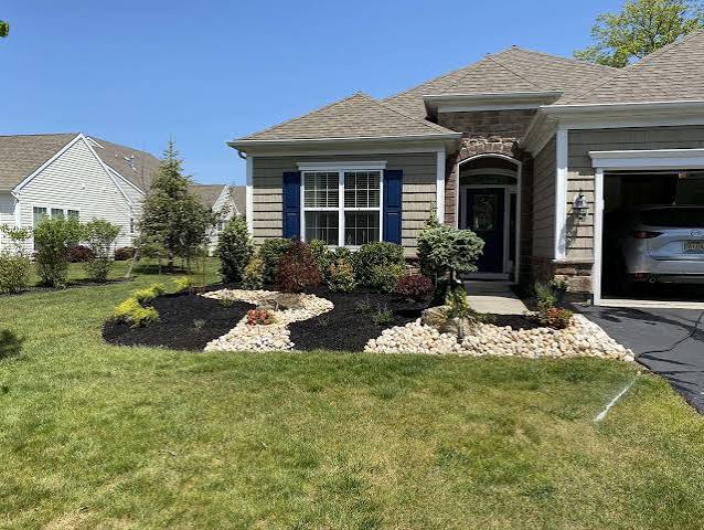 Front yard with mulched beds and decorative river rock swale